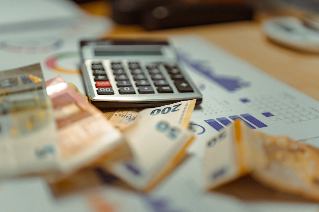 Photo by Jakub Żerdzicki A calculator sitting on top of a pile of money